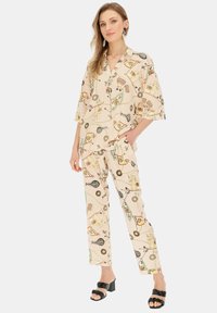 Dwuczęściowy strój składający się z koszuli z krótkim rękawem i kołnierzykiem oraz pasujących spodni. Tkanina ozdobiona kolorowymi wzorami na beżowym tle.