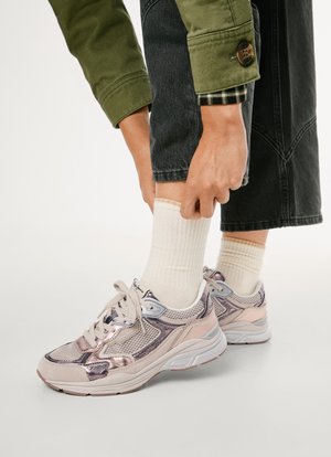 Võrgust ülemise osaga sneakerid, millel on metallik roosa ja hall disain, pehmed valged aksessuurid, ümar varvas ja paksud kummitaldad. Stiliseeritud soonikute valgete sokkidega.