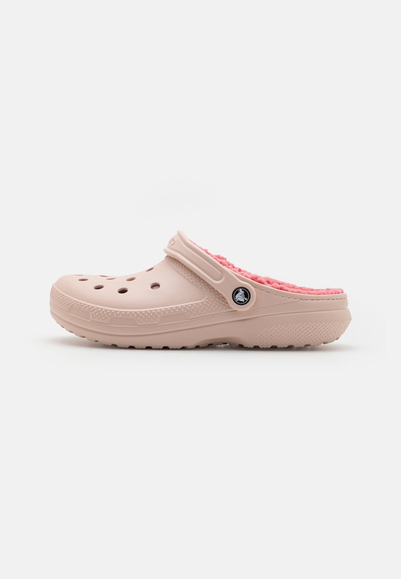 Sabot en mousse rose clair avec une surface texturée, de grands trous de ventilation et une doublure en peluche rose contrastante. Présente un accent de logo noir.