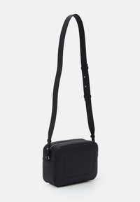 Black crossbody bag made of textured material, rectangular shape, featuring a zip closure and an adjustable strap.