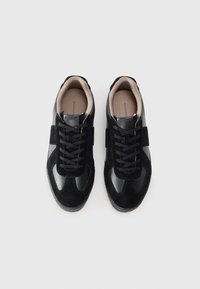 Baskets noires avec une combinaison de daim et de cuir. Présentent une semelle texturée, un bout arrondi et un design à lacets. Branding minimal à l'intérieur.