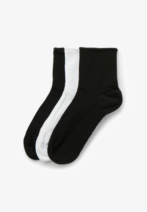 Due paia di calzini a coste fino al polpaccio, uno nero e uno bianco, con blocchi di colore a contrasto sui lati. Texture liscia, design senza cuciture.