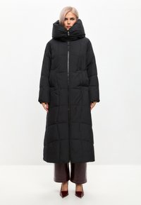 Černý polstrovaný dlouhý kabát s vysokým límcem, se zapínáním na plný zip vpředu, širokými rukávy a prošívanou texturou. Elegantní design s hladkým povrchem.