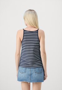Navy and white striped tank top with thin straps, made from a soft fabric. Paired with a light blue denim mini skirt featuring frayed hem.