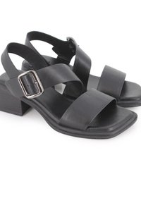 Sandalias de cuero negro con dos correas anchas, punta cuadrada y tacón medio cuadrado. Acento de hebilla ajustable en una de las correas.