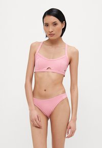 Růžový bikiny set s topem sportovního stylu a výřezem ve tvaru klíče, nastavitelnými ramínky a nízko střihanými kalhotkami, vyrobený z hladké tkaniny.