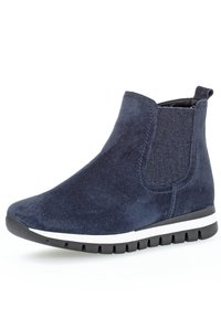 Bottine en daim bleu marine avec des panneaux élastiques sur les côtés, bout rond et semelle en caoutchouc blanc contrastant avec des rainures pour l'adhérence.