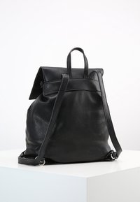 Schwarzer Leder-Rucksack mit strukturierter Oberfläche, ausgestattet mit verstellbaren Trägern, einem umklappbaren Deckel und einem geschwungenen Körperdesign.