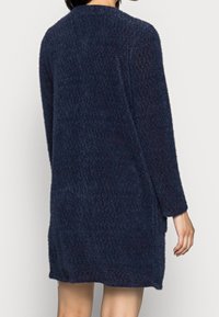 Marinblå, stickad cardigan med en strukturerad tyg. Har långa ärmar, rak skärning och rund halsringning. Längd nedanför höfterna.