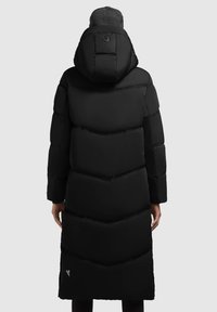 Črna puffer jakna z obliko chevron, dolga dolžina, velik pokrov in žep z zadrgo na strani. Ima logotip na hrbtu in rebraste manšete.