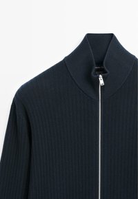 Dunkelblauer, gerippter Pullover mit hohem Kragen und silbernem Reißverschluss. Hergestellt aus 100 % Baumwolle mit glatter Textur und modernem Design.