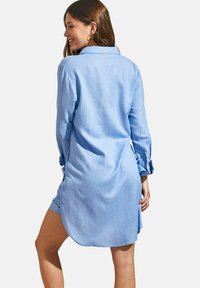 Lichtblauw linnen overhemdjurk met een kraag, lange mouwen, knoopmanchetten en zijsplitten; soepele textuur en ontspannen pasvorm.