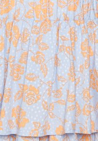Tessuto blu chiaro con pois bianchi in rilievo. Presenta un motivo floreale arancione con rose e foglie verdi, arricciato in vita.