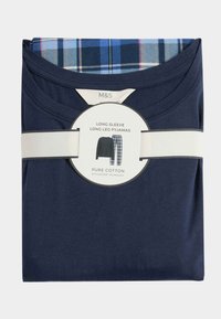 Pijamas de algodón de manga larga en azul marino con un patrón de cuadros en el cuello y la cinturilla, empaquetados con una banda blanca y una etiqueta circular.