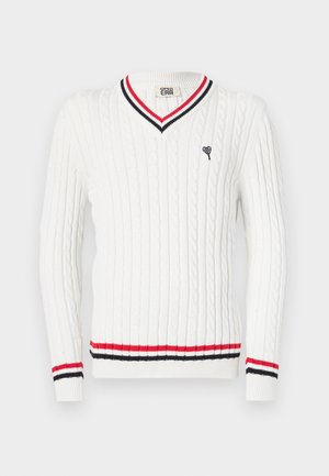 Baltos kabelių megztinis su V formos iškirpte, su raudonais ir juodais dryželiais apykaklėje ir apačioje. Mažas širdelės logotipas išsiuvinėtas krūtinėje.