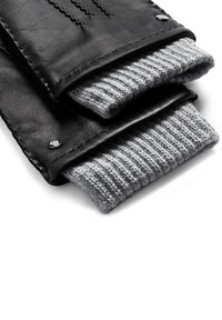 Schwarze Lederhandschuhe mit grauen gestrickten Bündchen, auf einem weißen Hintergrund gefaltet, der Nähte und Knopfdetails zeigt.