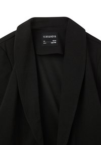 Blazer nero con colletto a taglio e tessuto morbido. Etichetta interna con taglia (12/13) e altezza (152/158 cm). Design pulito e vestibilità strutturata.