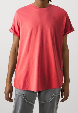 Korallefarbenes Kurzarm-T-Shirt aus weicher Baumwolle, mit umgeschlagenen Ärmeln, rundem Halsausschnitt und kleinem Logo auf der Brust.