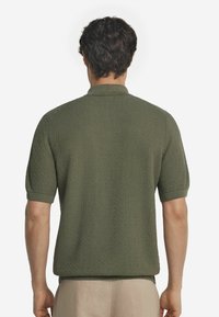 Mörkgrön texturerad polo skjorta med krage och korta ärmar, med ribbade manschetter och en något lös passform vid fållen.