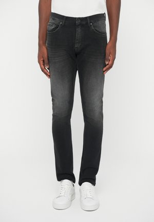 Svarta denimjeans med en urtvättad finish, slim fit, femficksdesign och knappstängning, i kombination med vita sneakers.