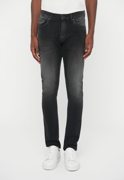 Black denim jeans with a faded finish, slim fit, five-pocket design, and button closure, paired with white sneakers.