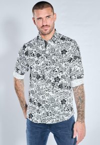 Schwarz-weiß gemustertes Hemd mit floralem Design, Knopfleiste und hochgekrempelten Ärmeln, gefertigt aus leichtem Stoff. Verfügt über einen klassischen Kragen.