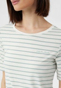 Koszulka z krótkim rękawem w białym kolorze z jasnoniebieskimi poziomymi paskami, okrągłym dekoltem i subtelnym haftowanym logo "przecinek" po lewej stronie klatki piersiowej.