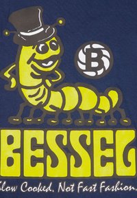 Camiseta de algodón azul con un gusano de dibujos animados en amarillo y un sombrero de copa negro, acompañado de un texto en negrita amarillo "BESSEG" y un eslogan debajo.