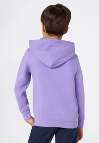 Felpa viola realizzata in tessuto morbido, dotata di cappuccio e polsini a costine. Il retro presenta un design pulito senza pattern o loghi visibili.