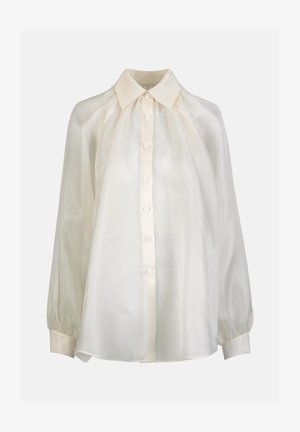 Krēmkrāsas, garām piedurknēm blūze ar pogu aizdari priekšpusē, smailu apkakli, savāktām plecu daļām un pogām apsienamiem aproču galiem.