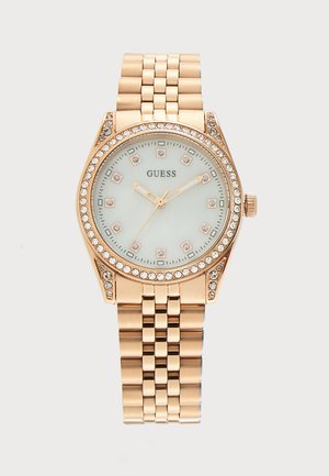 Ρολόι χειρός Guess με επίστρωση χρυσού, με κρυστάλλινα διακοσμητικά γύρω από τη στεφάνη και τους δείκτες της ώρας, συνδεδετό μπρασελέ και λευκό καντράν με τρεις δείκτες.