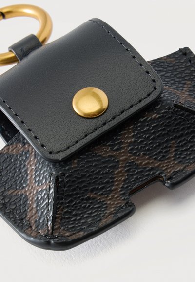 Porte-clés à motif noir et marron avec surface texturée, bouton-pression doré et anneau doré pour clés fixé à une fermeture à rabat en cuir noir.