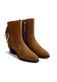 Botines de ante marrón con flecos a los lados, punteras afiladas y cremalleras en tono dorado. Cuentan con una suela plana negra para mayor estabilidad.