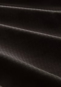 Dunkel strukturierter Stoff mit subtilen geometrischen Mustern, der sanfte Falten und eine glatte Oberfläche aufweist. Die Farbe ist ein tiefes Braun mit einem leichten Glanz.