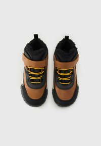 Botas de senderismo marrones y negras con cordones amarillos; cuentan con una tira de velcro, forro de tela texturizada y una suela robusta para mayor tracción.