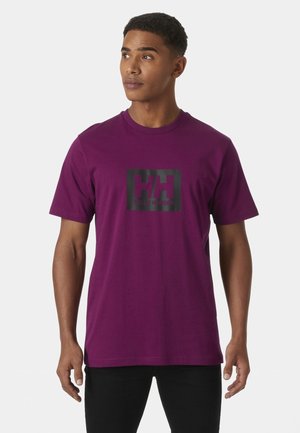 T-shirt viola in cotone con un logo rettangolare nero che presenta "HH" e "Helly Hansen" in lettere grassetto. Maniche corte e scollo rotondo.
