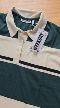 Žalias ir smėlinis dryžuotas polo marškinėliai su apykakle, dviem mygtukais ir juodu akcentu. Pridedamas etiketė su užrašu "WEEKDAY".