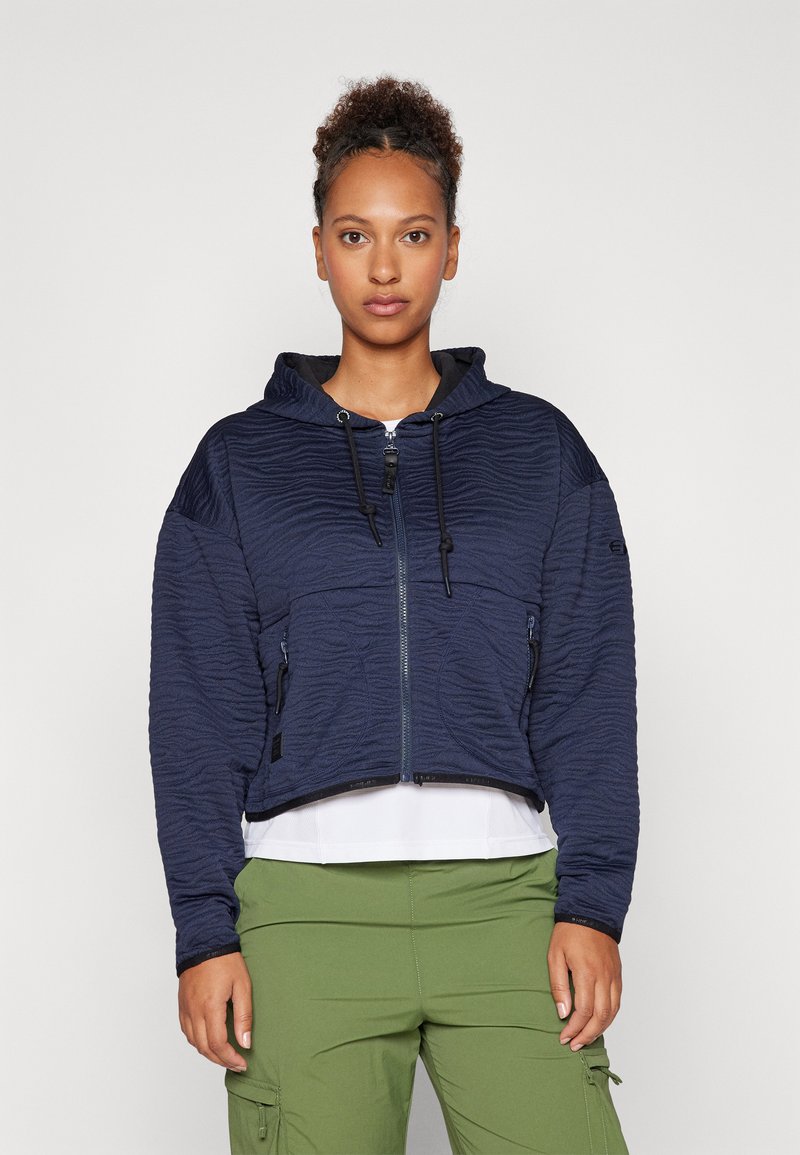 Marineblå cropped hettegenser med teksturert bølgedesign, frontlås med glidelås, justerbare snorer og to lommer med glidelås.