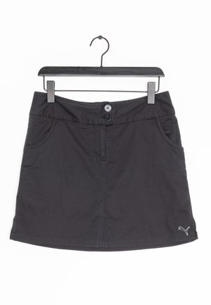 Zwarte rok van het merk Puma met twee knopen en voorzakken, hangend aan een zwarte plastic hanger tegen een witte achtergrond.