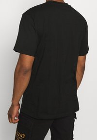 Camiseta de algodón negra con cuello redondo, mangas cortas y corte relajado, con un diseño liso y textura suave.