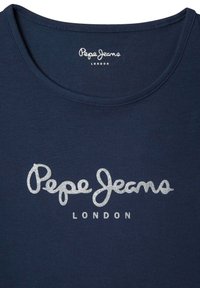 Tums zilas T-krekls, kas izgatavots no mīkstas auduma, ar sudraba mirdzošo "Pepe Jeans" logotipu un tekstu "LONDON" zem tā. Apaļa izgriezne, īsas piedurknes.