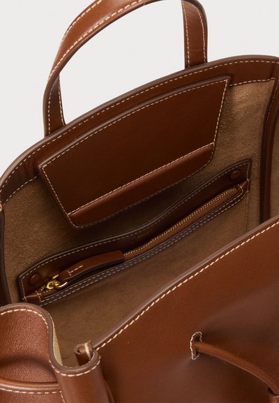 Καφέ δερμάτινη τσάντα tote με υφή, διαθέτει τσέπη με φερμουάρ και δύο εσωτερικά διαμερίσματα. Διπλές ραφές για επιπλέον ανθεκτικότητα.