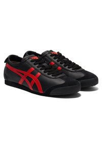 Black leather and suede sneakers with red accents, featuring laces, a rounded toe, and a textured rubber sole.