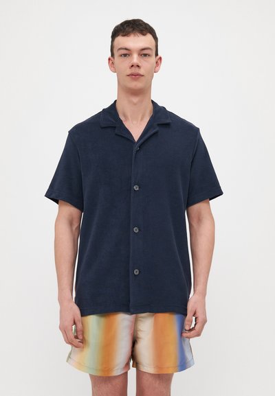 Marinblå kortermet skjorte med knapper laget av frotté, med krage og frontknapper, kombinert med shorts med regnbuestreker.