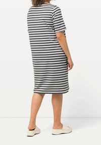 Pasekowy, krótki rękaw sukienka w odcieniach szaro-czarnych, do kolan, o luźnym fasonie. Modelka nosi jasne buty wsuwane.