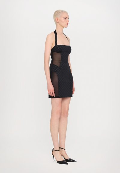 Rochie mini neagră cu decolteu halter, având un model în carouri, cu panouri laterale transparente. Însoțită de pantofi cu toc ascuțit negri, cu bretele pentru glezne.