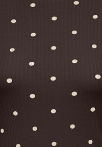 Brązowy prążkowany top z równomiernie rozmieszczonymi dużymi kremowymi grochami. Powierzchnia ma teksturowany wygląd.