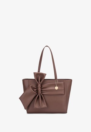 Borsa tote in pelle marrone con un grande dettaglio a fiocco su un lato. Presenta una superficie liscia, doppio manico e un accessorio a charm dorato.