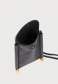 Melns ādas kartīšu turētājs ar strukturētu dizainu, apaļiem zelta toņa metāla akcentiem un gludu apdari. Atvērts augšējais daļa ar vienu nodalījumu.