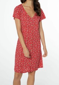Robe fleurie rouge avec un décolleté en V, des manches courtes et une fermeture boutonnée à l'avant. Présente de petits motifs blancs et jaunes sur un tissu texturé.